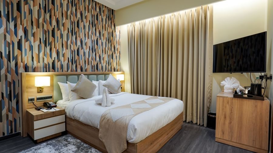 Full view of the Deluxe room featuring a double bed along with a beige coloured bed runner spread over it at M2 Square by Monday Premium.
