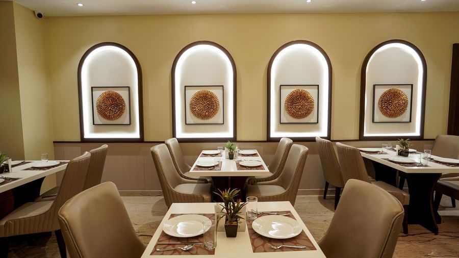 A close-up shot of a neatly arranged dining table featuring plates kept on table mats and a small plant in the middle at M2 Square by Monday Premium.