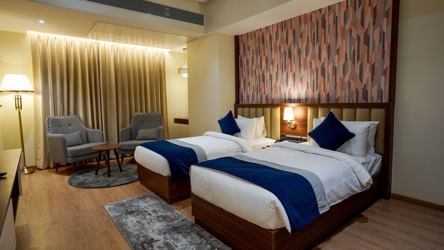 Full view shot of Superior Twin Bed Room featuring a twin bed along with 2 cushioned armchairs at the far end of the room at M2 Square by Monday Premium.