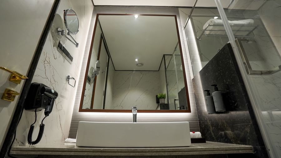 A sleek bathroom featuring a washbasin and a back-lit mirror in the bathroom of the Premium Room at M2 Square by Monday Premium.