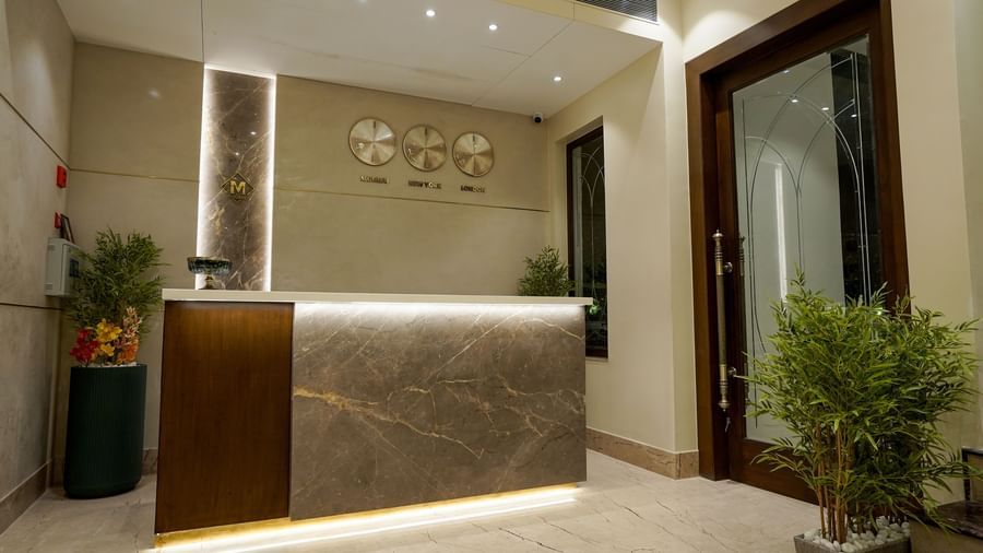 Corner view of the reception desk at M2 Square by Monday Premium with a huge glass door beside it.