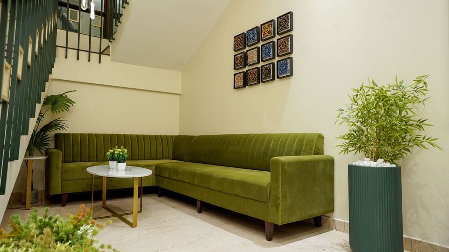 An L-shaped couch with a coffee table in front of it beside a flight of stairs at M2 Square by Monday Premium.