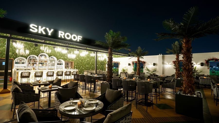 A wide angle shot of Sky Roof during the night with various tables arranged in an open air space at M2 Square by Monday Premium.