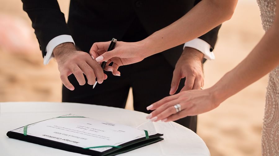 close up image of the bride and groom signing the marriage certificate kept on the table - Maikhao Dream Villa Resort & Spa, Phuket