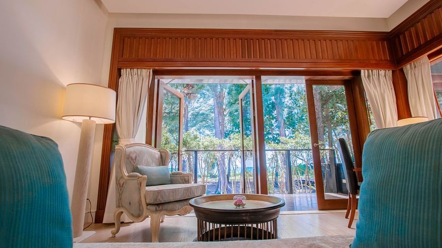 An armchair in front of a coffee table with french windows in the back - two bedroom private pool beachfront villa