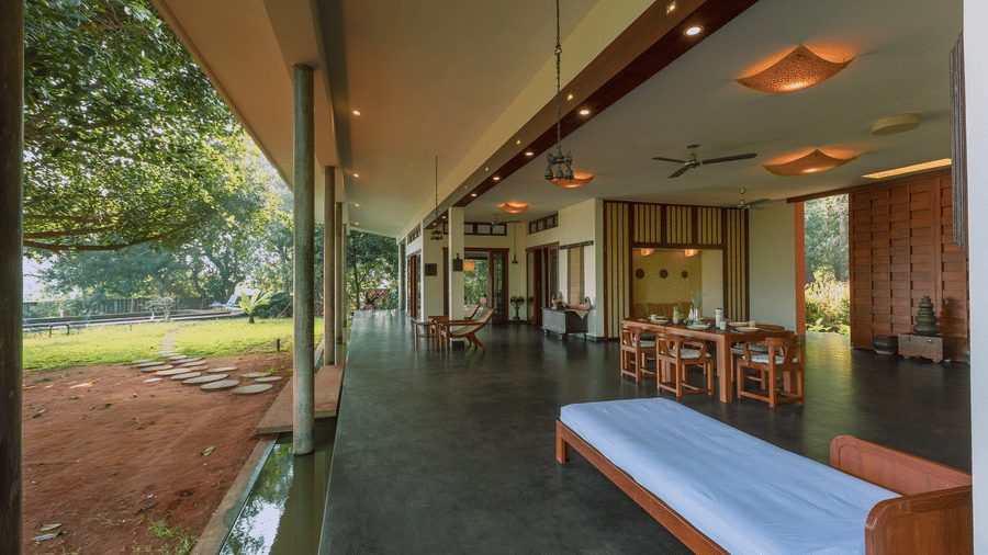Villa Wuwei at Mango Hill Auroville, Pondicherry featuring an outdoor seating area has a long bench and chairs, with open walls overlooking the garden.
