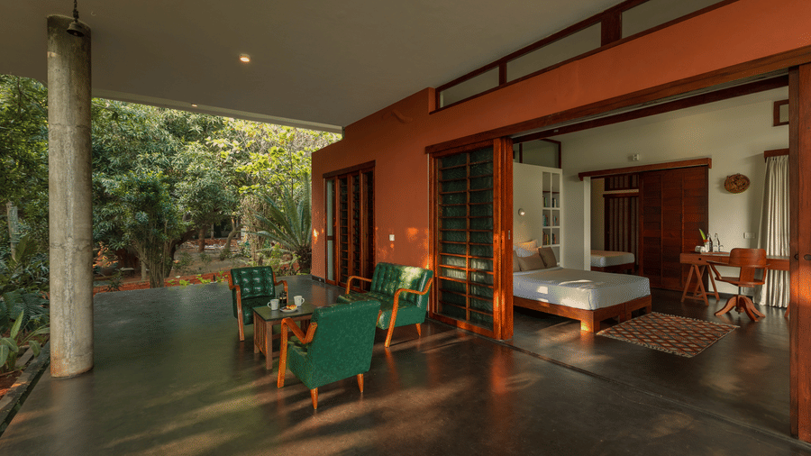 The living of Villa Wuwei at Mango Hill Auroville, Pondicherry featuring a space opens to the garden and contains chairs, a sofa, and a ceiling fan.