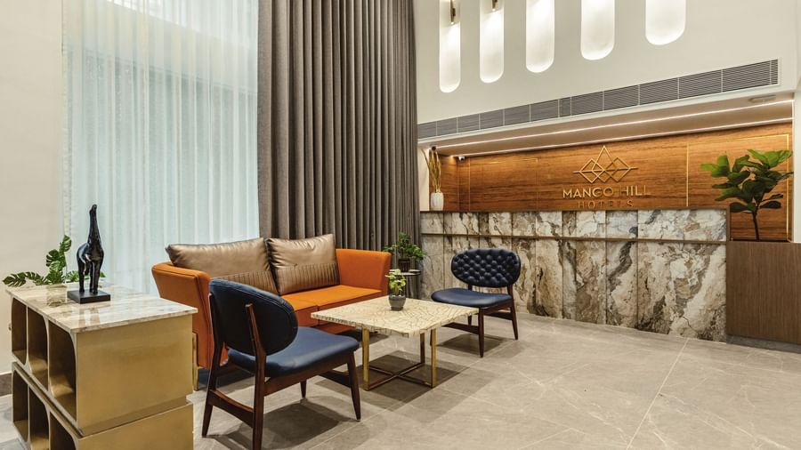 A seating area in the lobby at Mango Hill Central, Chennai, with a reception desk in the background and a sofa and chairs in the foreground.