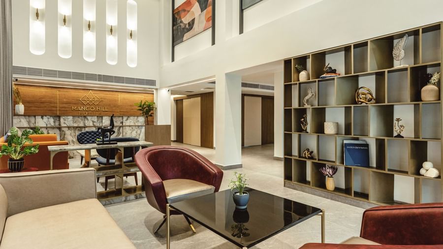 A seating area in the lobby at Mango Hill Central, Chennai, with a large bookcase behind it. There are sofas and chairs around a coffee table.