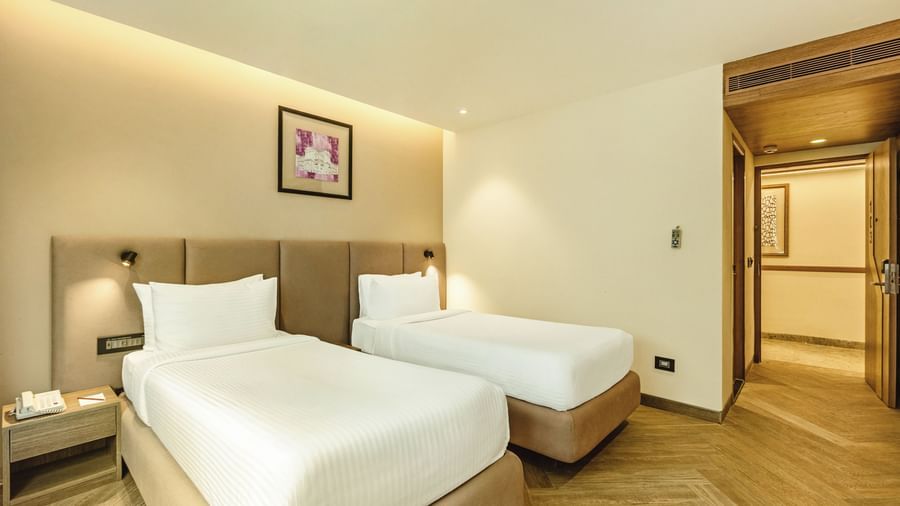 A twin-bedded room with a television and a desk, seen from an angle, at Mango Hill Central, Chennai.