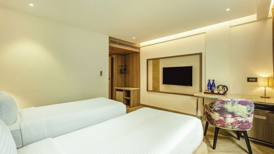 A twin-bedded room with a television and a desk, seen from an angle, at Mango Hill Central, Chennai.