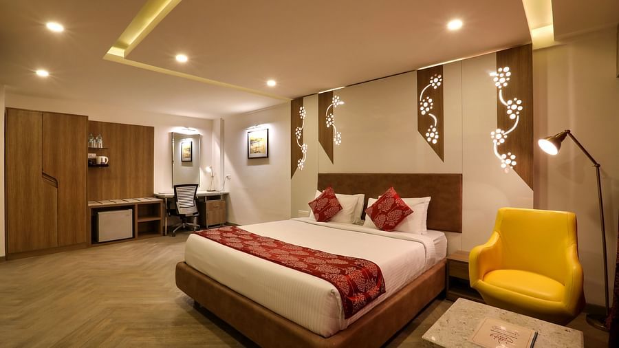 A  bedroom with a king size bed and a sofa and small table on the side, with a workdesk and chair on the other end - Mango Hill Central, Chennai