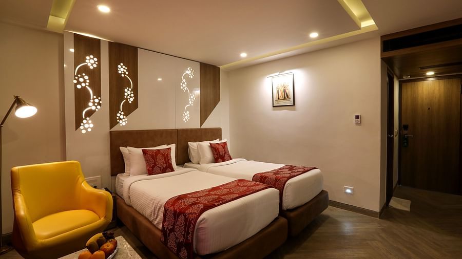 A bedroom with two single beds and a sofa and small table on one end beside the windows - Mango Hill Central, Chennai