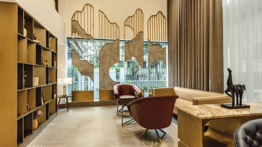 A lobby seating area at Mango Hill Central, Chennai. There is a sofa, two chairs, and a desk in the foreground.