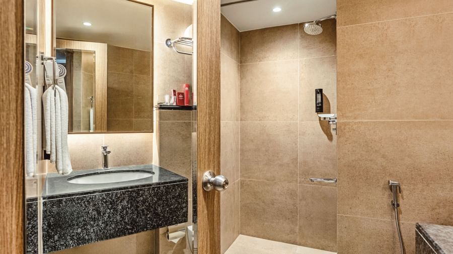  A close-up of the sink, mirror, and shower area in a bathroom at Mango Hill Central, Chennai.