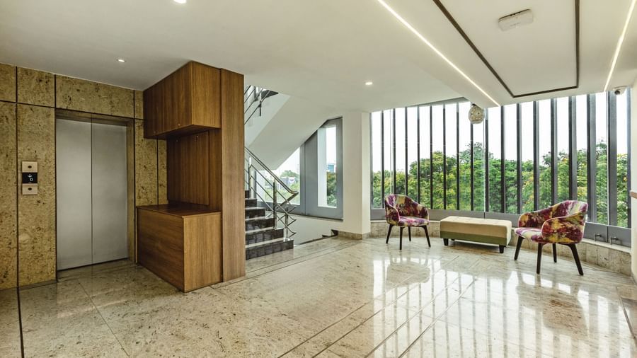 A view of a seating area with large windows in Mango Hill Central, Chennai. An elevator is visible on the left.