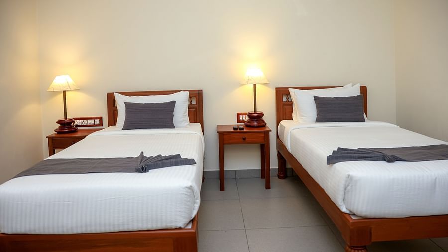 Twin beds with bedside table for each in a room  | Mango Hill La Serene, Pondicherry