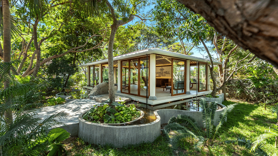 Modern glass-walled building surrounded by lush greenery at Mango Hill Shallow Beach Resort ECR