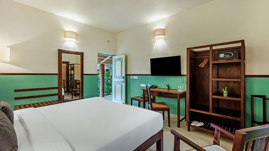 Comfortable bedroom with a king bed, wooden desk and chair, a flat-screen TV, a wardrobe with a safe, and a partially open door | Mango Hill Shallow Beach Resort ECR