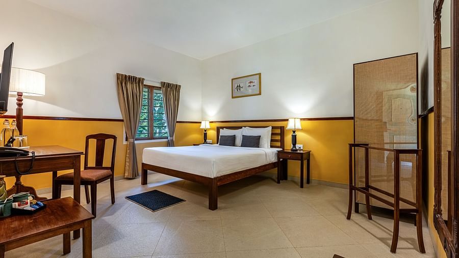 Comfortable bedroom in Pondicherry featuring a double bed, a writing desk, chairs, and a full-length mirror | Mango Hill Shallow Beach Resort ECR
