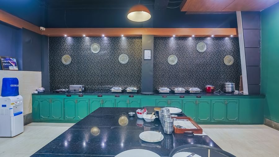 Buffet counter with serving dishes and plates at Max Hotel Prayagraj.
