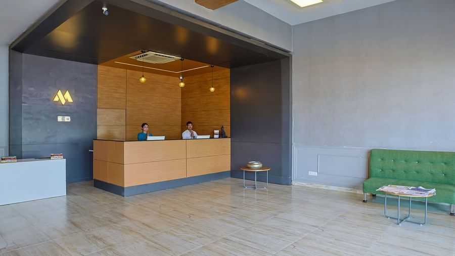 Reception desk with wooden finish and seating at Max Hotel Prayagraj.