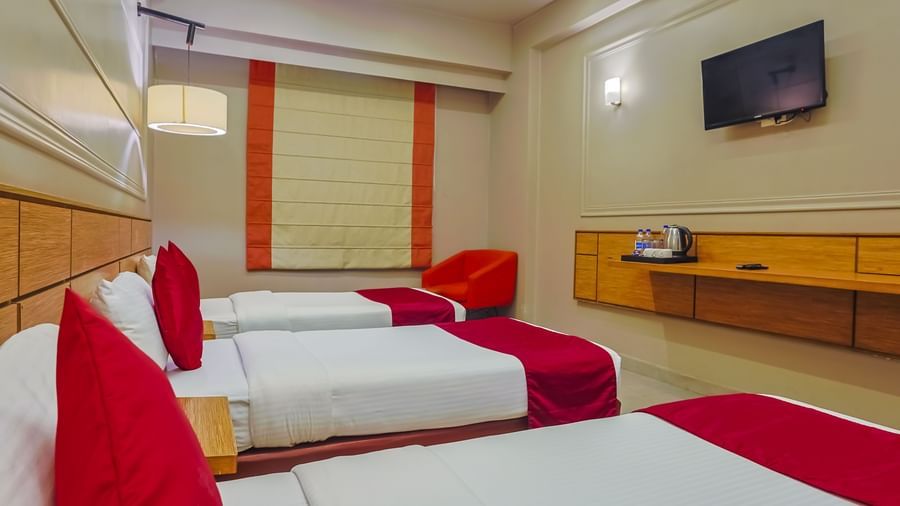Room with red and white bedding, flat-screen TV at Max Hotel Prayagraj.