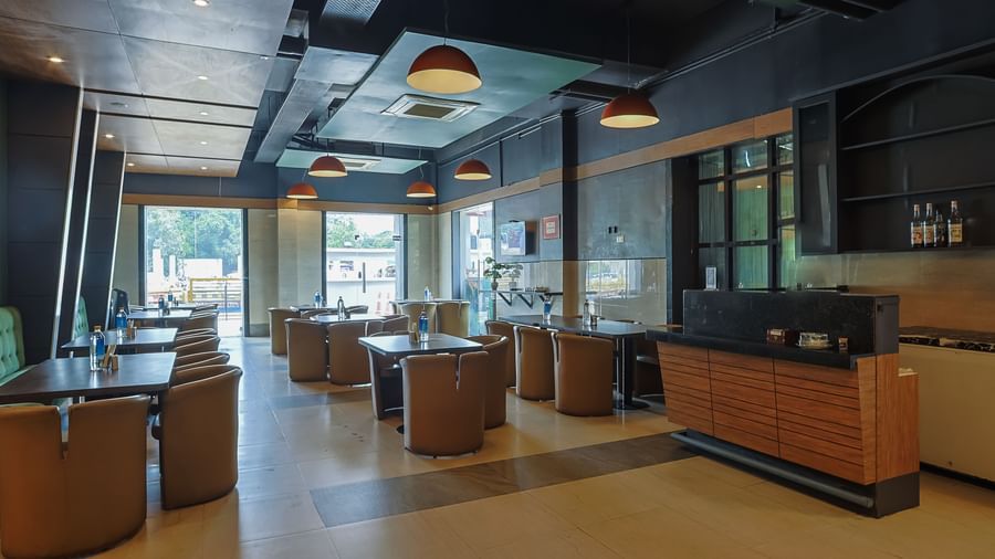 Spacious restaurant with tables, chairs and large windows at Max Hotel Prayagraj.