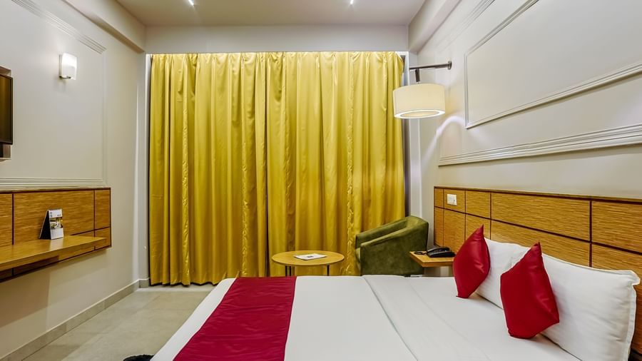 Well-lit spacious room with elegant yellow drapes at Max Hotel Prayagraj.