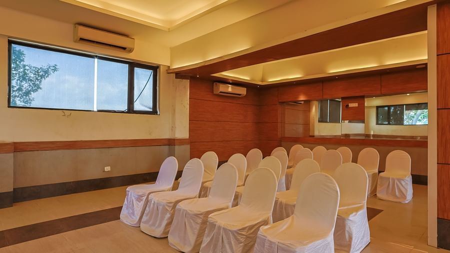 Banquet hall with seating arrangement, glossy floor and ceiling lights at Max Hotel Prayagraj.