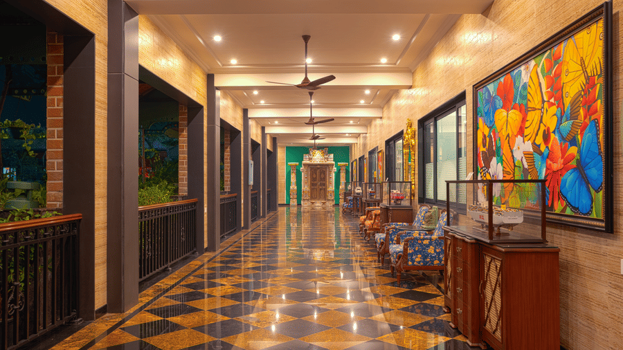 A long, narrow corridor with a chequered floor, bright lighting, and abstract, colourful artwork hanging along the wall at MAYFAIR Bay Resort, Paradeep.
