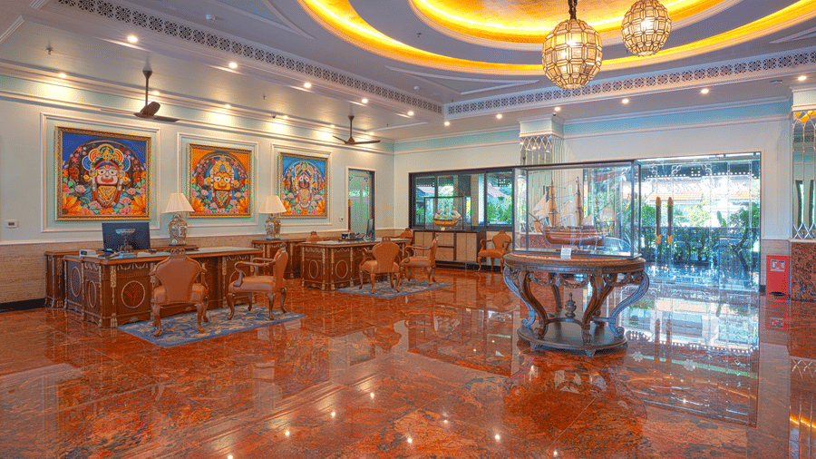 A wide view of the lobby lounge with seating area, decorative artwork, and a polished reddish marble floor at MAYFAIR Bay Resort, Paradeep.
