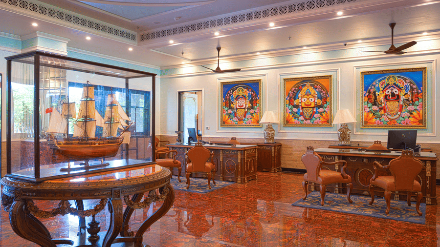 A lobby seating area with desks, upholstered chairs, and colourful, traditional artworks mounted above the furniture at MAYFAIR Bay Resort, Paradeep.