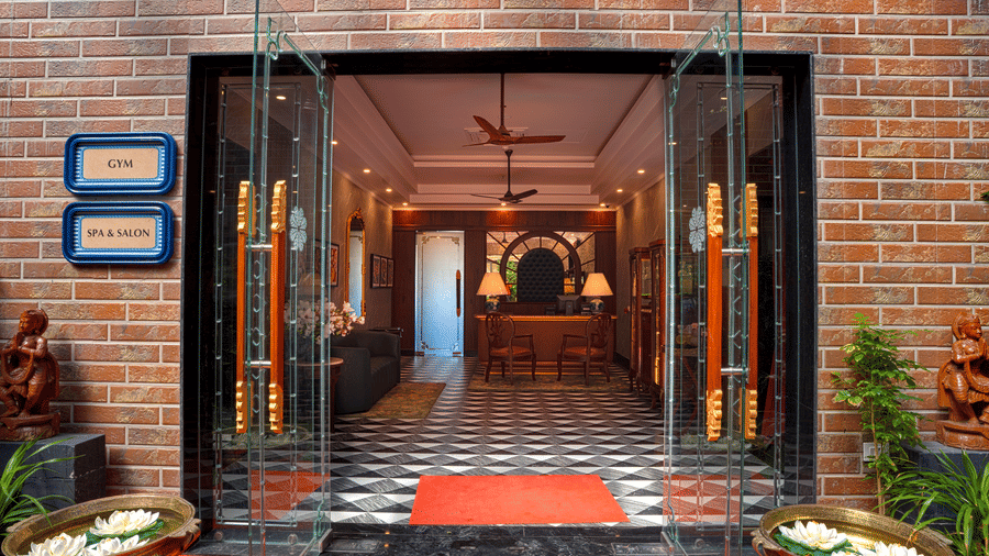 The entrance of a spa building with a red carpet leading through an open doorway, framed by a brick wall at MAYFAIR Bay Resort, Paradeep.
