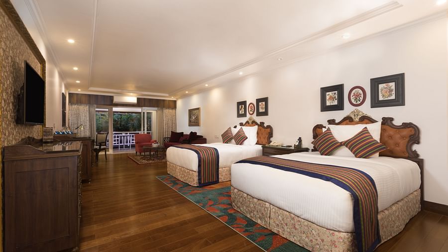 twin beds facing the TV with the walls of the room decked with paintings - Mayfair Himalayan Spa Resort Kalimpong