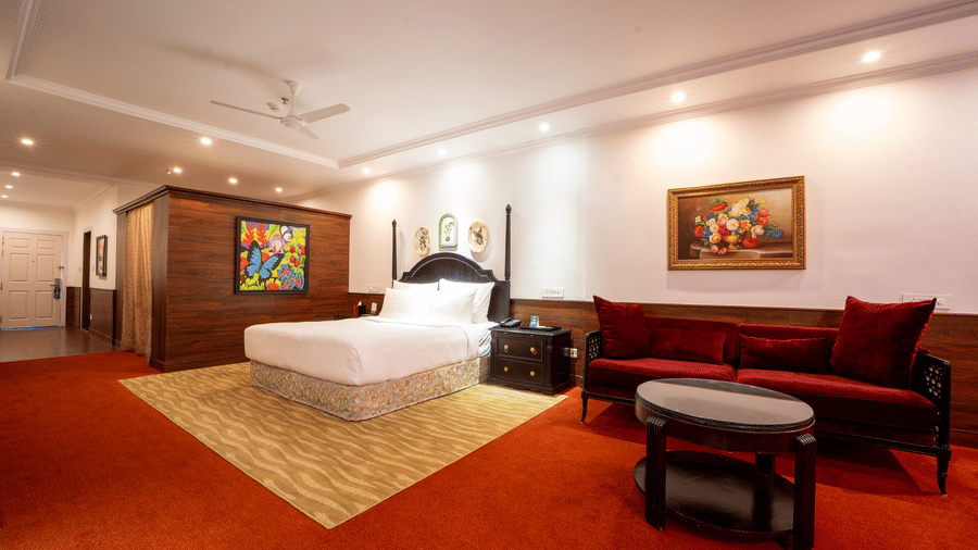 Standard Room at MAYFAIR Himalayan Spa Resort Kalimpong featuring a bed, bedside table, and a sofa with a centre table.