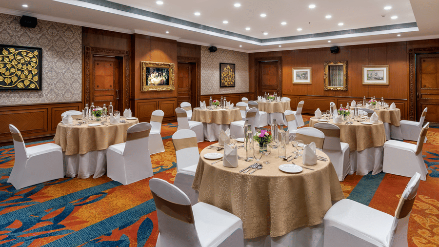 Elegant indoor banquet hall Lavender at Mayfair Lagoon Bhubaneswar with round tables, floral centerpieces and warm ambient lighting