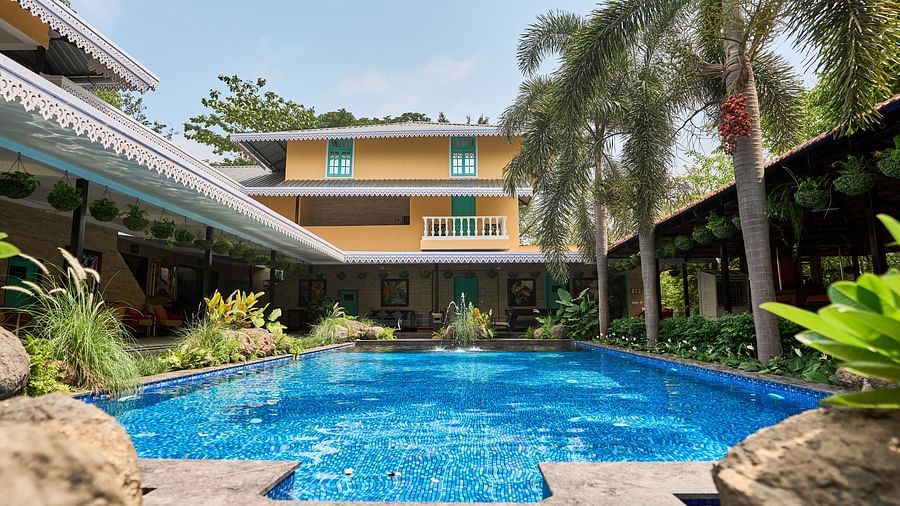 Swimming pool with a facade, surrounded by plants and trees at Mayfair Manor, Alibag