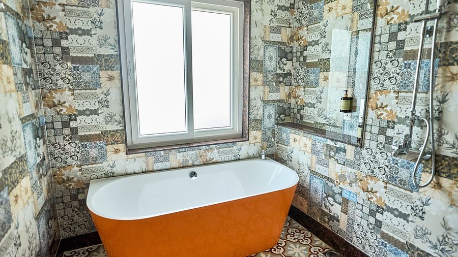A bathtub with a sliding window behind it at Mayfair Manor, Alibag