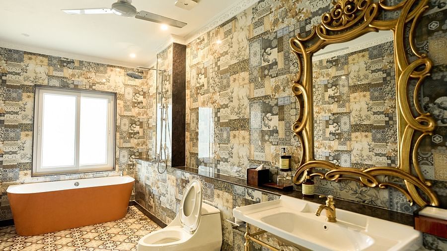 A spacious bathroom with a bathtub, Western toilet, and a washbasin with a wall-mounted mirror above it at Mayfair Manor, Alibag