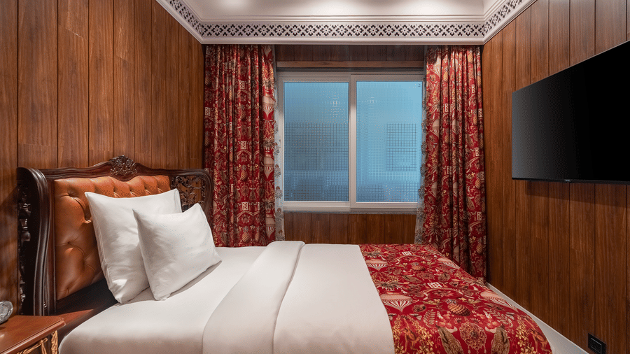 Warmly decorated guest room featuring a king bed and wooden panelling at Mayfair Manor, Jungpana.