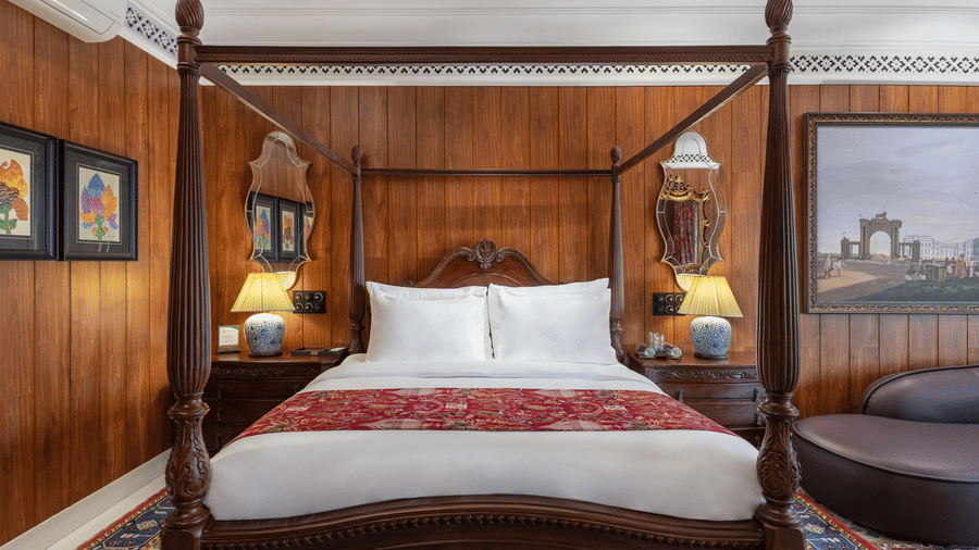 Warmly lit suite with a carved wooden four-poster bed at Mayfair Manor, Jungpana.