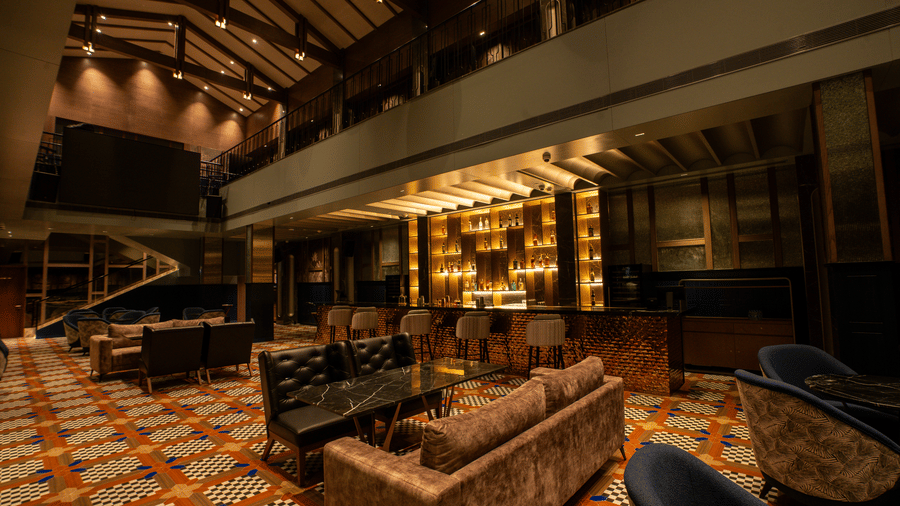 Indoor bar lounge with sofas, tables, and ceiling lights at Origyn, Merlis Hotel, Coimbatore.