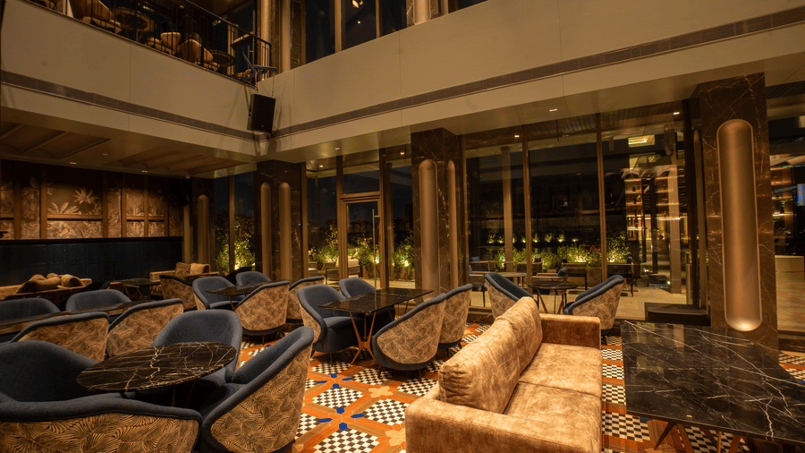 Seating area with sofas, tables, and lighting inside Origyn bar at Merlis Hotel, Coimbatore.