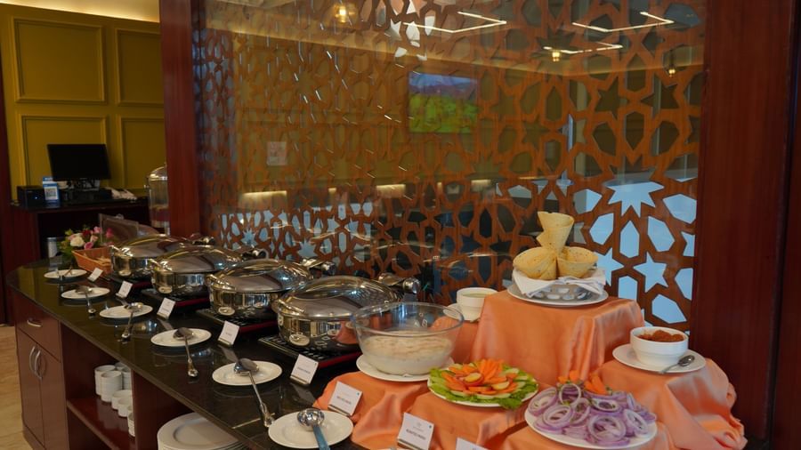 A wide shot of a buffet table with a variety of serving dishes. The background has a decorative wooden screen.