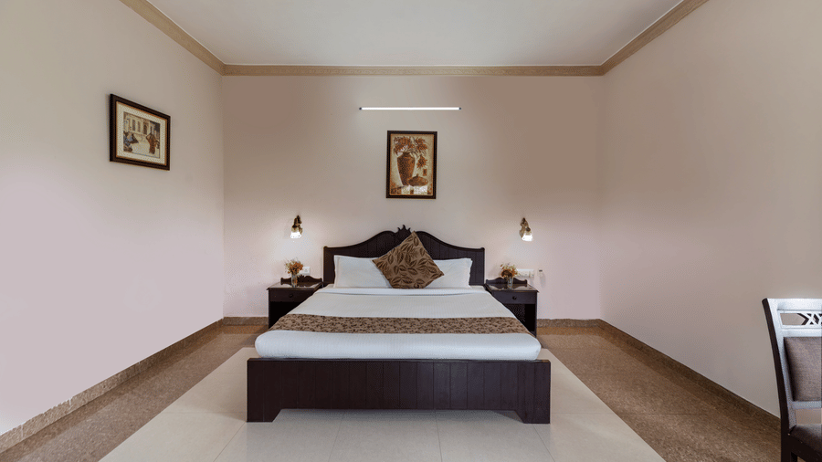 A comfortable guest room at Mewar Mansion Villa By Amantra, Udaipur offers a large bed and a cosy window alcove.