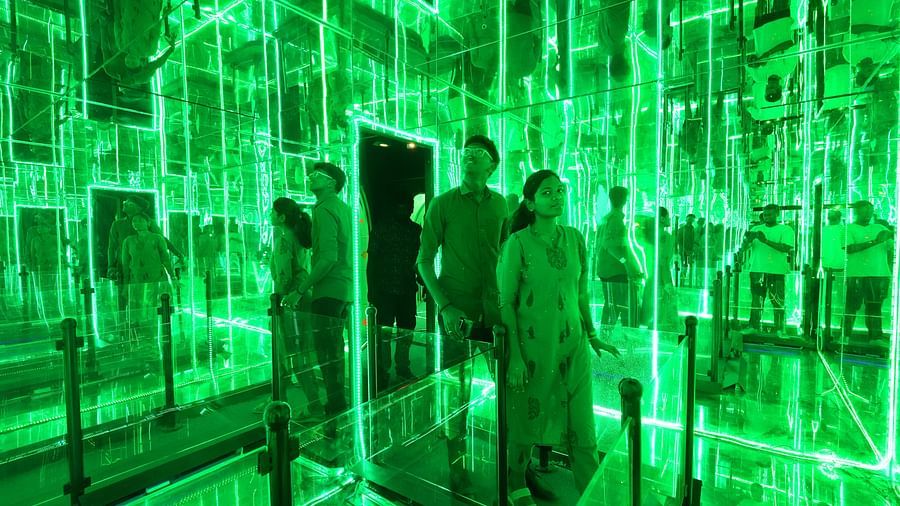 A couple in infinity room at MGM Dizzee World featuring mirrors on all three sides and a pathway on the fourth side, just like how labyrinths are.