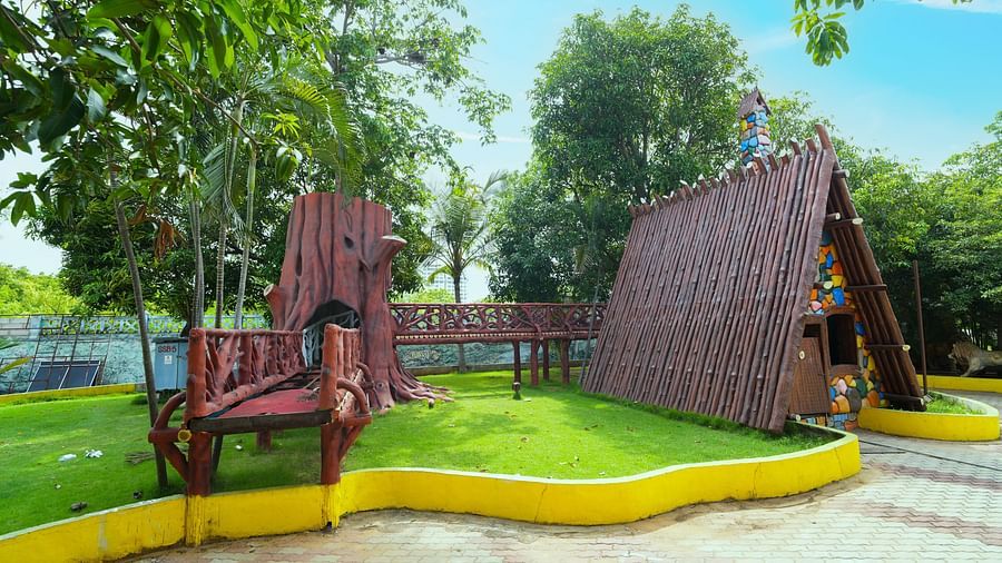 A charming garden scene at MGM Dizzee World featuring large wooden swings, a shaded hut-like structure, and well-maintained greenery — ideal for relaxation and photo opportunities amidst a vibrant outdoor setting.