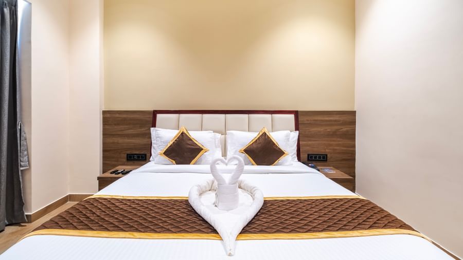 Luxury bed setup at Monday Hotels Amalapuram Heights with soft lighting and bed-side table.