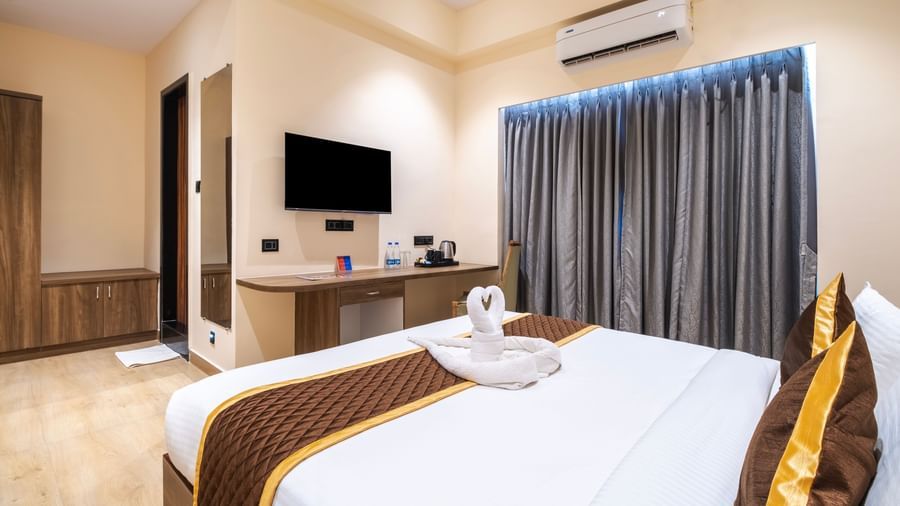 Spacious room at Monday Hotels Amalapuram Heights with TV, curtains, and double bed.